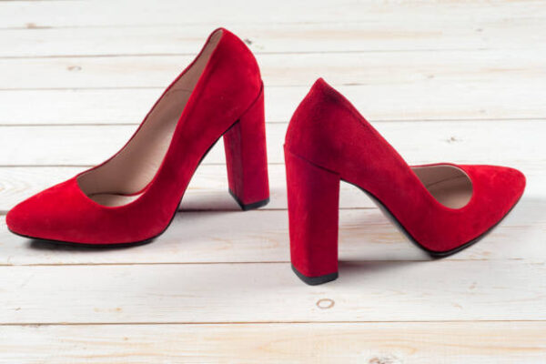 Red female shoes on high heels isolated on white wooden background
